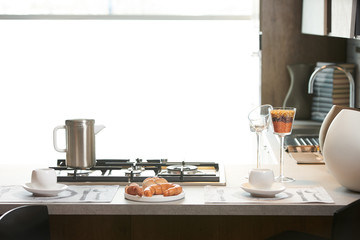 Delicious croissant and a two cup of coffee on a kitchen counter. Healthy breakfast with coffee in sunny morning for two person in modern kitchen interior