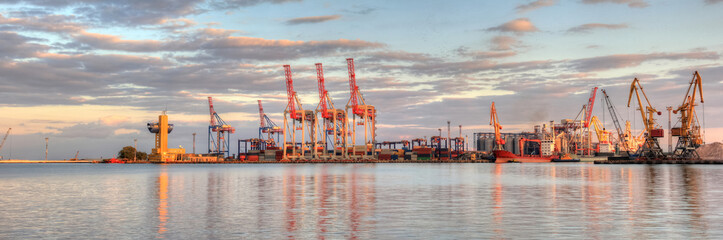 Wall Mural - Loading grain to the ship in the port. Beautiful view of the ship, cranes, and other infrastructures of the port on sunset