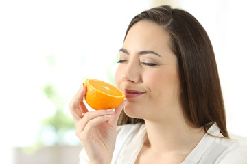 Wall Mural - Pretty woman smelling half orange at home