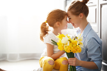 Wall Mural - happy mother's day! child daughter gives mother a bouquet of flowers to narcissus and gift