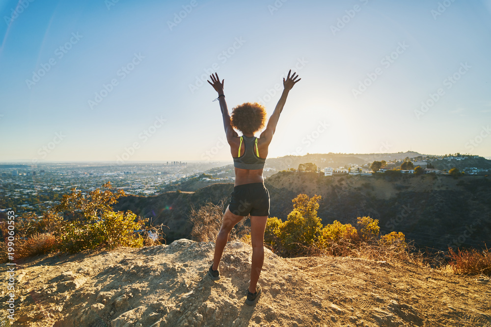 athletic african american woman celebrating reaching top of runyon canyon with arms open - obrazy, fototapety, plakaty 