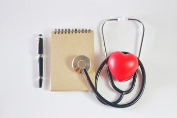 Flat lay photo with notebook, pen, Stethoscope and Red Heart Ball on white background in Healthcare concept