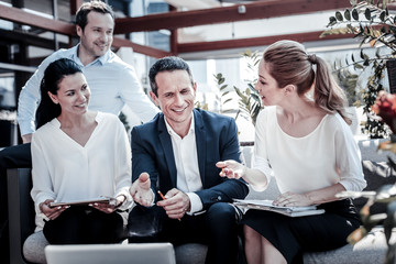 Wall Mural - New project. Nice positive smart businesspeople looking at the laptop screen and having a conversation while discussing a new project