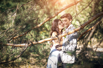 Beautiful young couple in the rays of the sun. Sunny wedding day in the park.