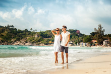 Beautiful Young Couple Walking On The Shore Of The Tropical Sea During A Honeymoon