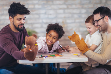 Two fathers play educational games with their children, having fun.