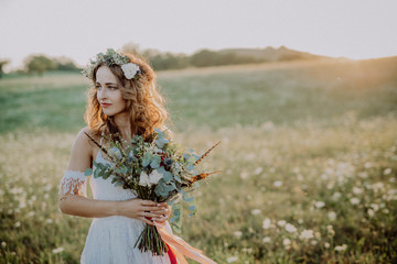 Wall Mural - Beautiful young bride at sunset in green nature.