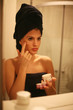 © liderina - Young woman applying cream in bathroom.