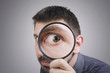 Portrait of a curious man looking through magnifying glass
