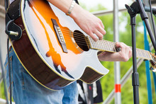 Musical Band Perfom On An Open Air Festival. Guitarist Man Playing Music By Wooden Acoustic Guitar Close-up
