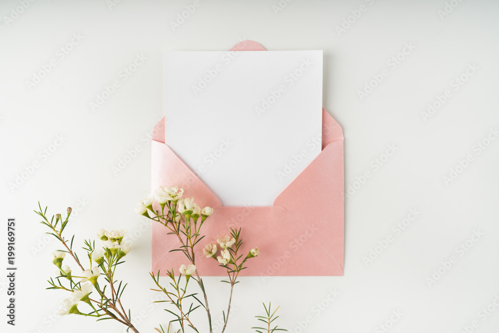 Minimal composition with a pink envelope, white blank card and a wax flower on a white background. Mockup with envelope and blank card. Flat lay. Top view. - obrazy, fototapety, plakaty 