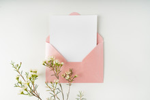 Minimal Composition With A Pink Envelope, White Blank Card And A Wax Flower On A White Background. Mockup With Envelope And Blank Card. Flat Lay. Top View.