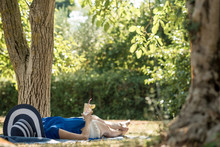 Woman Lying Relaxing In The Shade Of A Tree In A  Garden
