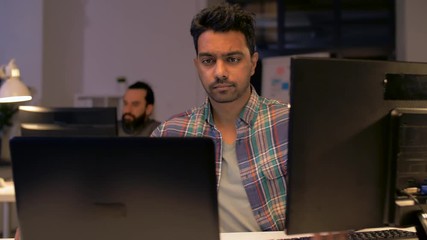 deadline, technology and people concept - creative man or programmer with laptop computer working at night office