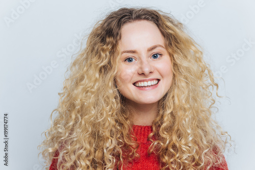 Delighted Pleased Adorable Woman With Curly Blonde Hair And Warm
