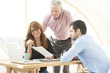© sepy - Close-up ofmiddle aged businesswoman consulting with senior manager and young assistant while sitting at office desk and working together on new project. Teamwork.
