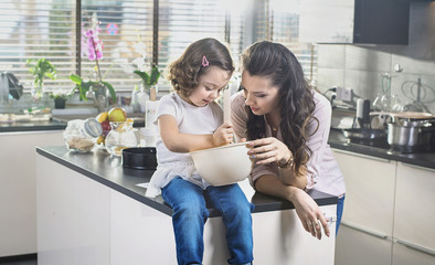 Wall Mural - Mother and daughter whisking cake in the bowl