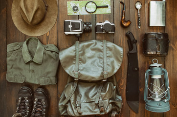 Wall Mural - camping stuff arranged on wooden backdrop. machete, shirt, boots, lantern, smoking pipe, hat, map, c