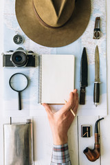 Wall Mural - adventure planning flat lay. travel vintage gear on map. traveler, explorer hand in frame holding em