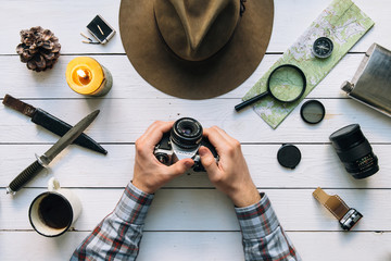 Wall Mural - adventure planning flat lay. travel vintage gear on white wooden table. man hands in frame holding v