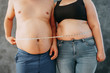 Overweight couple standing together wrapped with measure tape. Dieting, family weight losing and health care concept