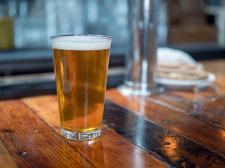 Full pint glass of beer sitting on bar counter