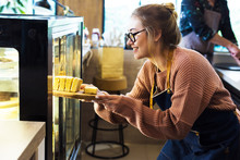 Woman Getting Cake Out Of The Display Fridge