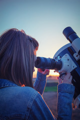 Wall Mural - cute young woman holding astronomical telescope and looking at the sky.