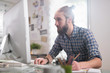 © jackfrog - Young man sitting at his desk in front of his computer