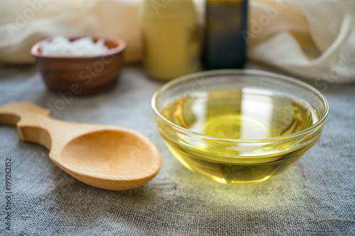 Fotografie, Obraz Liquid coconut MCT oil in round glass bowl with wooden spoon and bottles