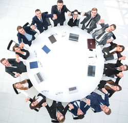 Poster - Director and business team sitting at the round table and holding each other's hands.