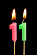 Burning candles in the form of 11 eleven figures (numbers, dates) for cake isolated on black background. The concept of celebrating a birthday, anniversary, important date, holiday, table setting