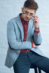 Fototapete - Bearded young man wearing stylish glasses by brick wall