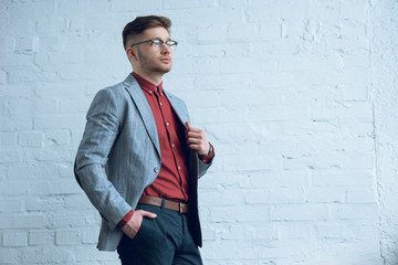 Fototapete - Stylish man in casual clothes wearing glasses by brick wall