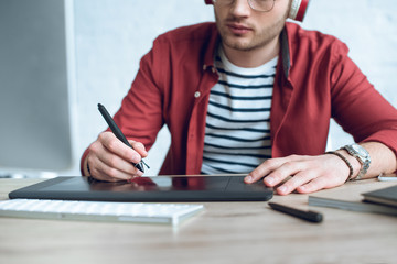 Fototapete - Young illustrator sitting by table with graphic tablet
