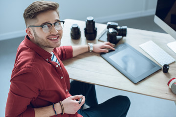 Fototapete - Happy freelancer man sitting by working table with graphic tablet