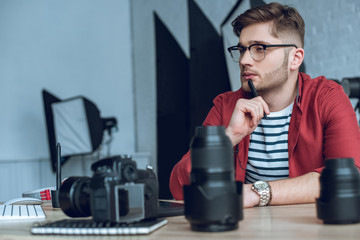 Fototapete - Thoughtful freelancer working by table with camera