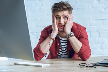 Fototapete - Stressed man sitting by working table with computer