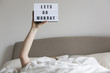 © ink drop - Female in bed under the sheets holding up a lets go monday sign