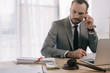 © LIGHTFIELD STUDIOS - selective focus of lawyer in suit looking at money at workplace with laptop in office