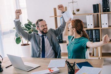 happy lawyer and client at workplace with documents and laptop in office