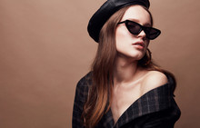 Fashion Portrait Of Beautiful Young Woman In Black Leather Beret Cap, Plaid Jacket And Cat Eye Retro Sunglasses With Massive Golden Earrings