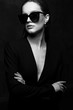 Sexy elegant black and white portrait of young beautiful woman in black deep v neck jacket and dark sunglasses