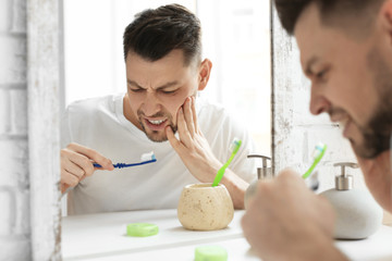 Wall Mural - Young man suffering from toothache in bathroom