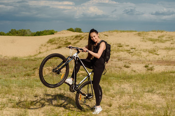 Wall Mural - Bicyclist at the summer sunset on the desert road in the reserve territory. Full length image of female bicycle. Extreme mountain bike sport athlete woman riding outdoors lifestyle trail