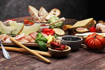 Italian antipasti wine snacks set. Cheese variety, Mediterranean olives, pickles, Prosciutto di Parma with melon, salami.