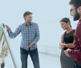 Wall Mural - happy man in checkered shirt standing in office near flipchart