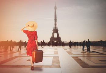  Redhead girl with suitcase in Paris with Eiffel tower on background. Concept of travelling around the World