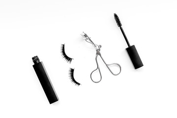 Cosmetics and tools for voluminous lashes. Mascara, false eyelashes, eyelash curler on white background top view space for text