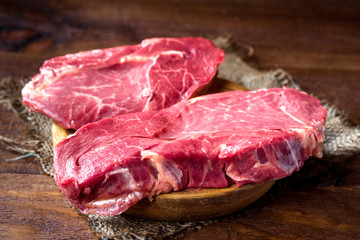 uncooked horse meat steaks on rustic wooden board